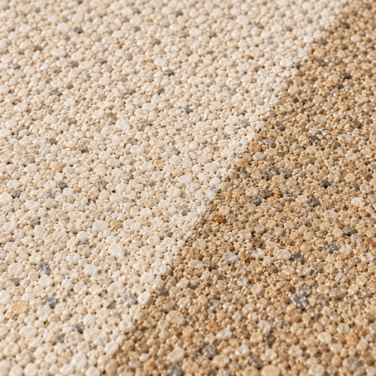 Gros plan PIETRORA : grains de pierre ivoire rencontrant une bordure de grains sable