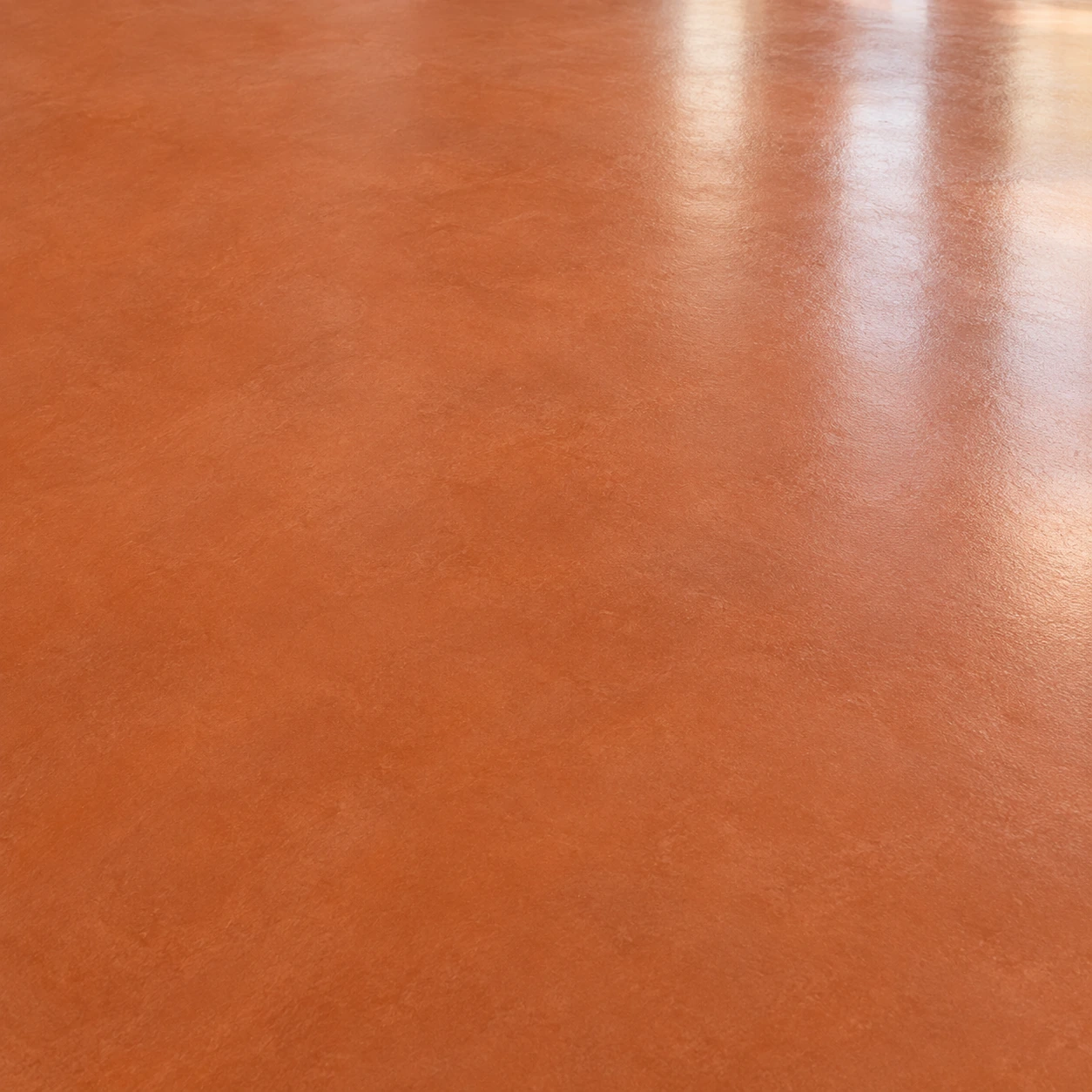 Détail d’un sol en résine terracotta lisse, légèrement nuancé et satiné.