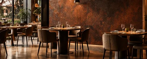 Salle de restaurant au mur rouille et cuivre, tables dressées et chaises en cuir sous des suspensions